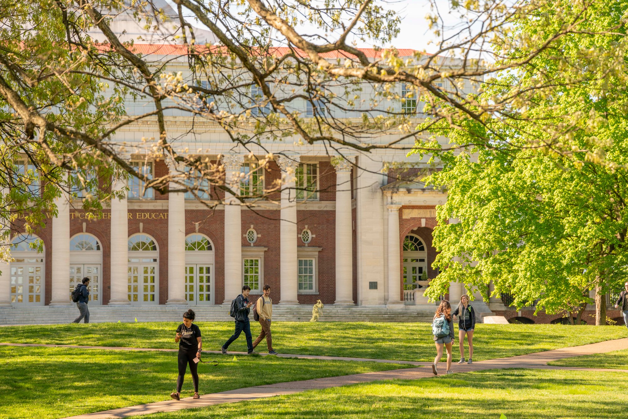 A group of people walking on the grass in front of a building.