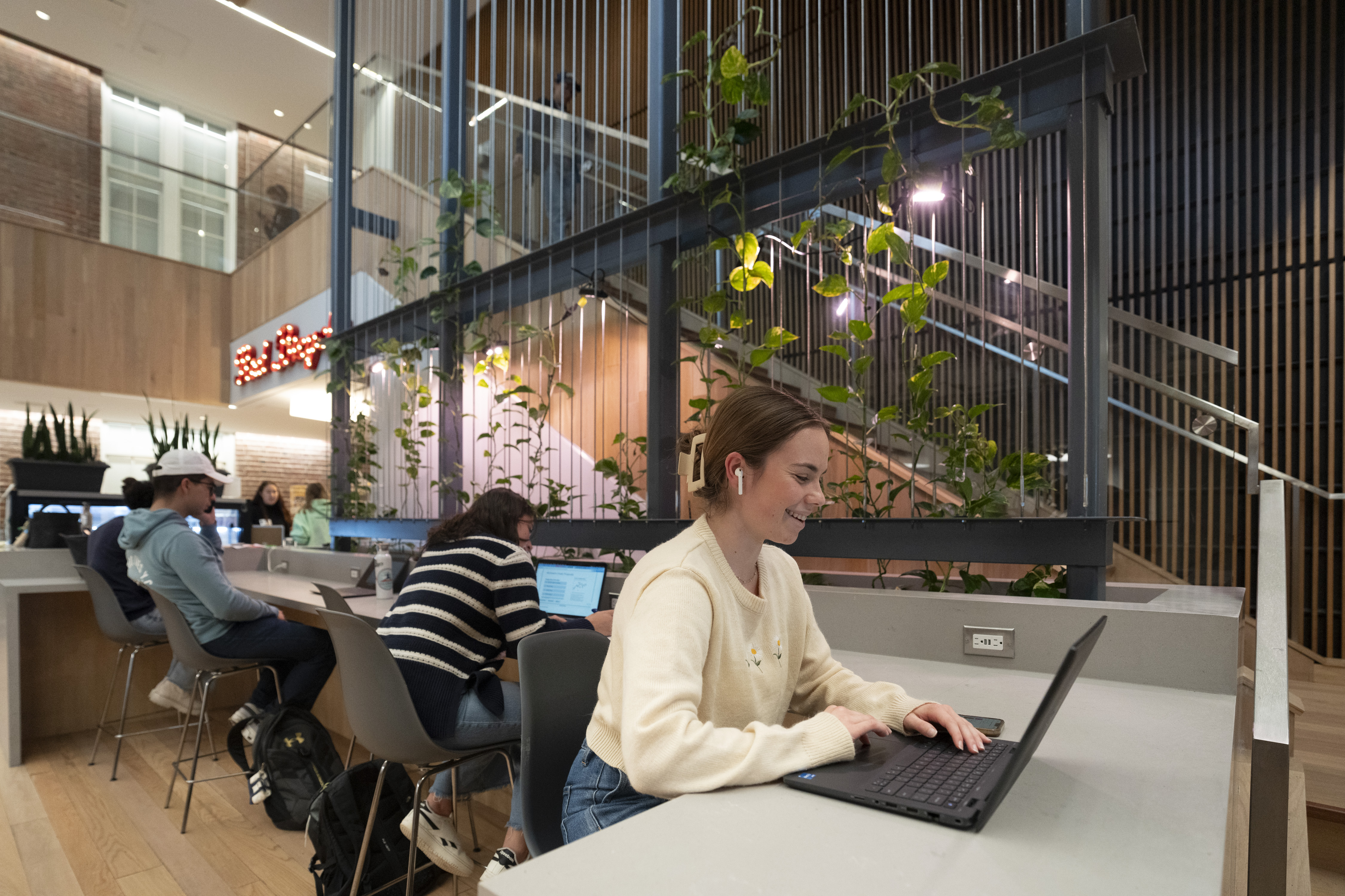 group of students sitting in an open space working on their laptops at a counter